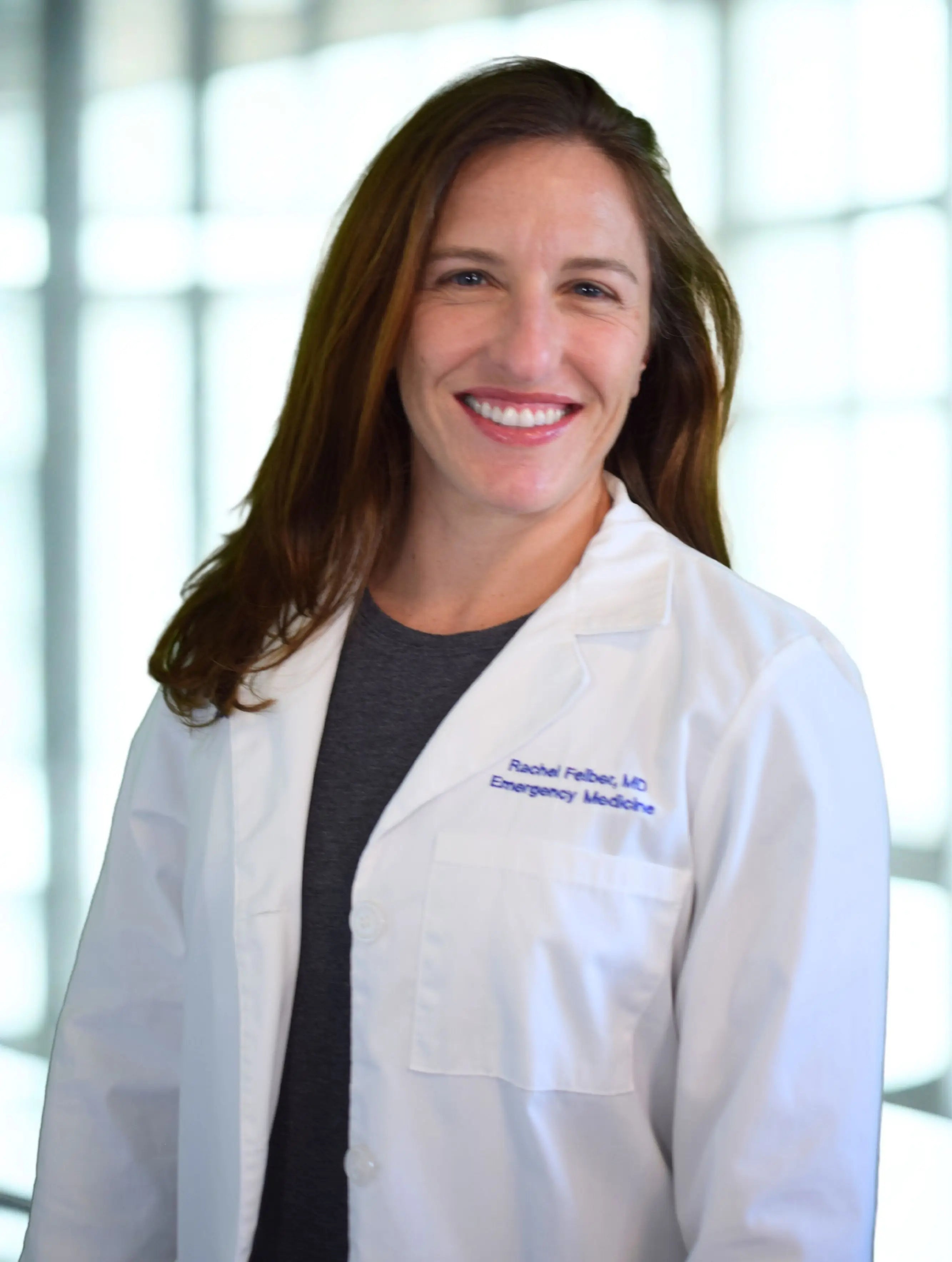 Dr. Rachel Felber, MD, in a white lab coat embroidered Rachel Felber, MD, Emergency Medicine